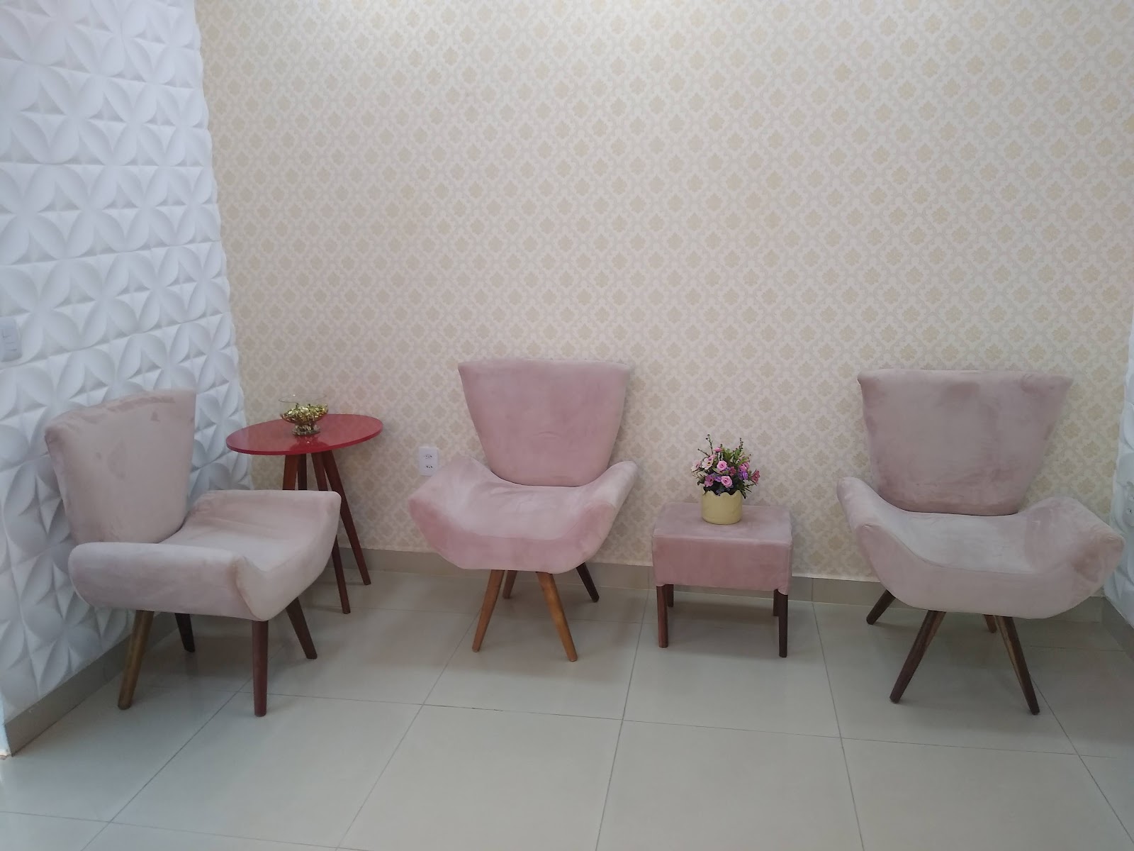Sala de espera do salão com poltronas de veludo rosé, parede clara e um arranjo de flores